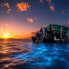 Cayman Adventure Tours booking policy - tour boat anchored at sunset over glowing blue bioluminescent water in Grand Cayman